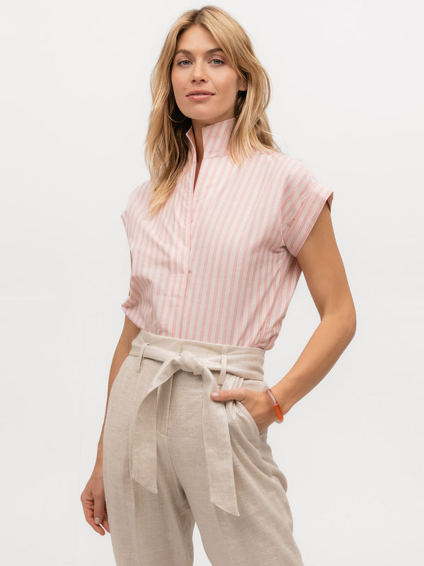 Model wearing a striped pink and cream designer cap sleeve top