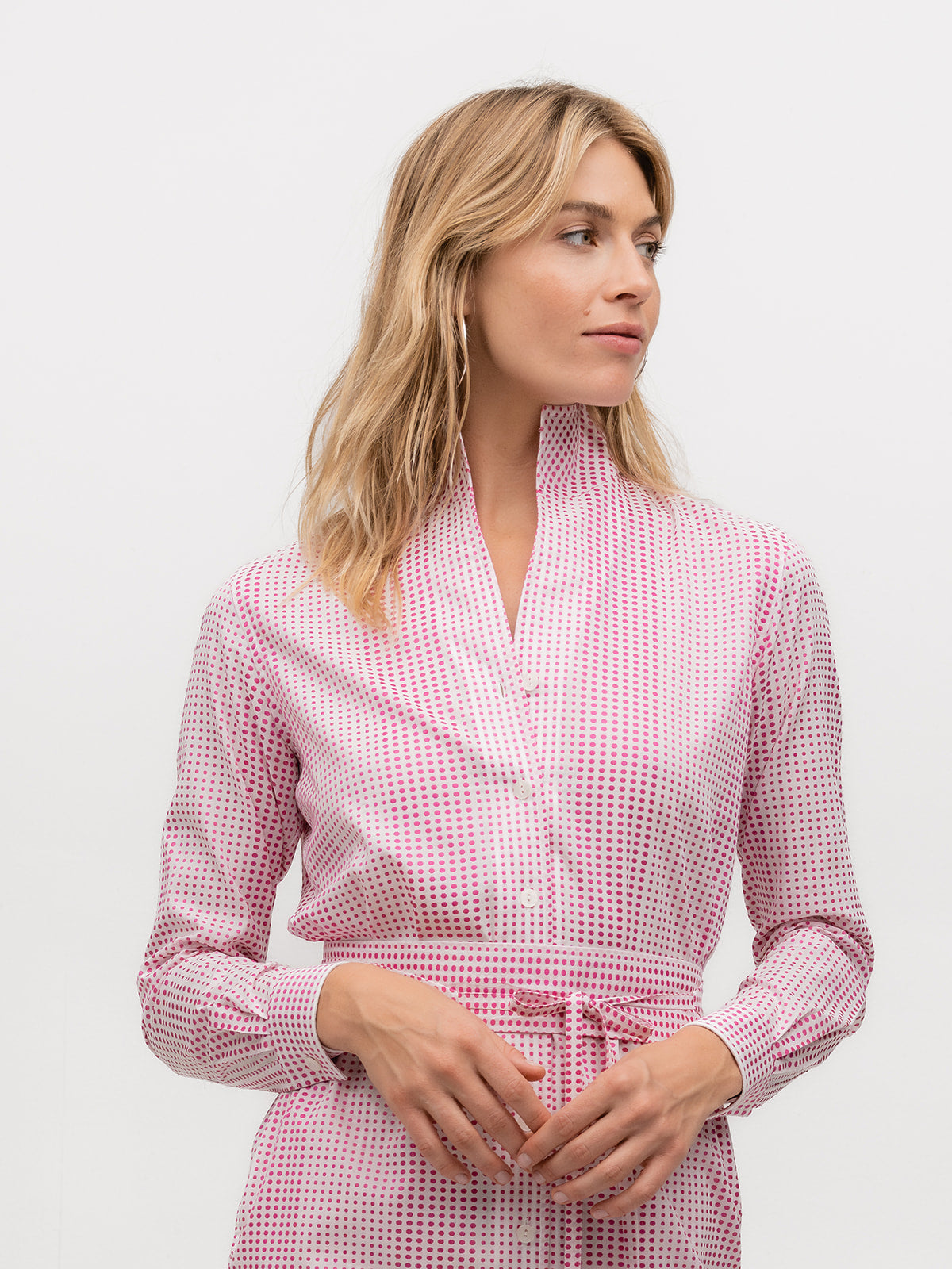 Woman wearing a button down designer shirt dress with pink and white polka dots