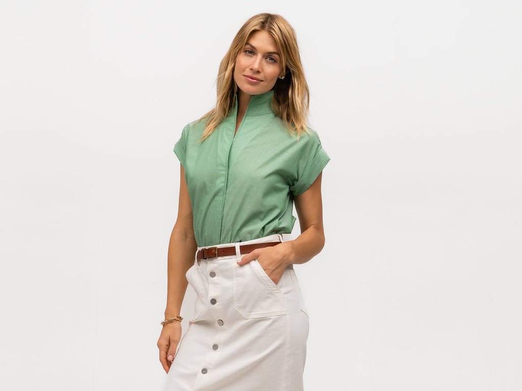 Model wearing a tucked in designer green short sleeve top
