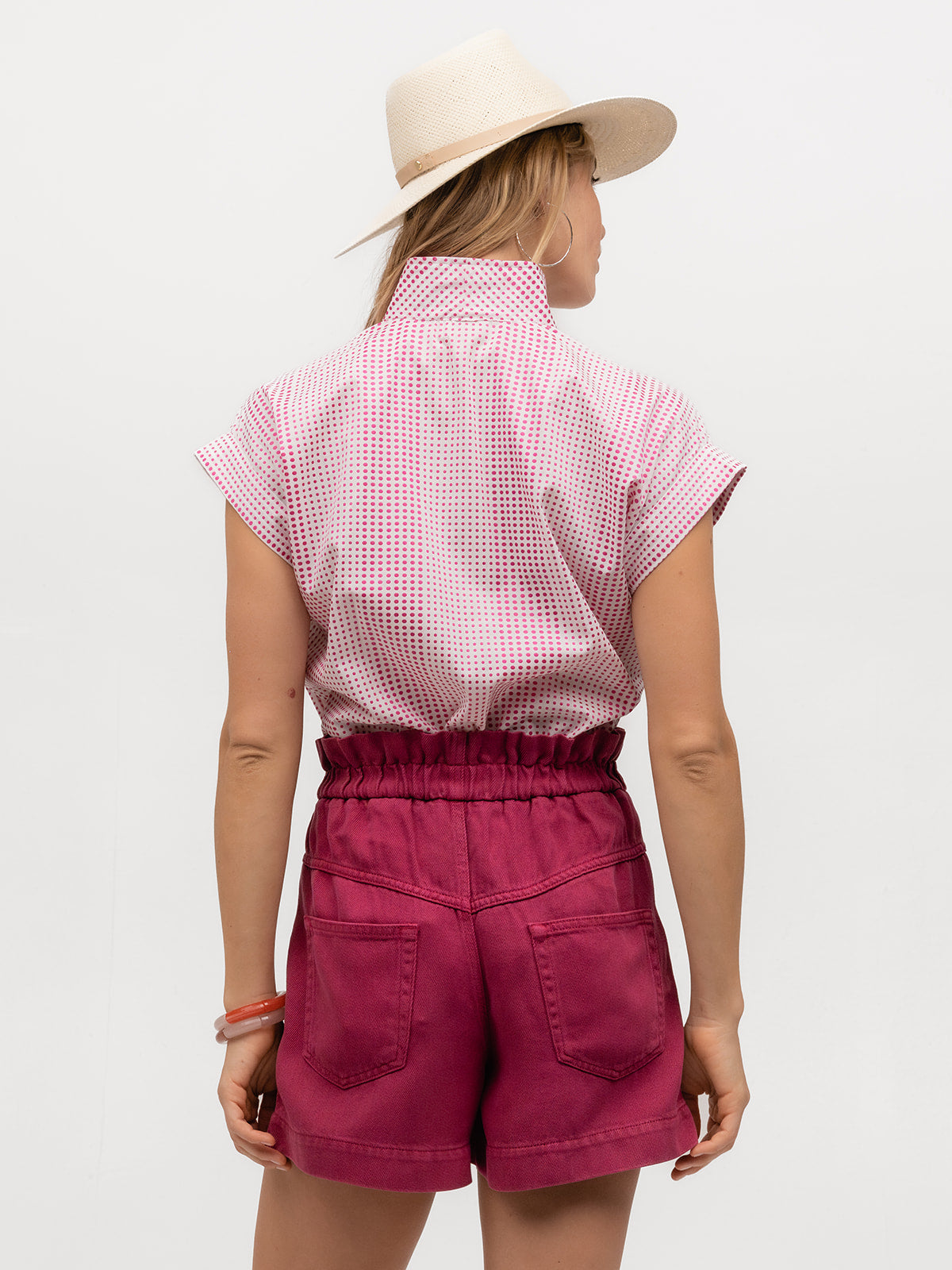 Back of a designer cap sleeve shirt with magenta polka dots