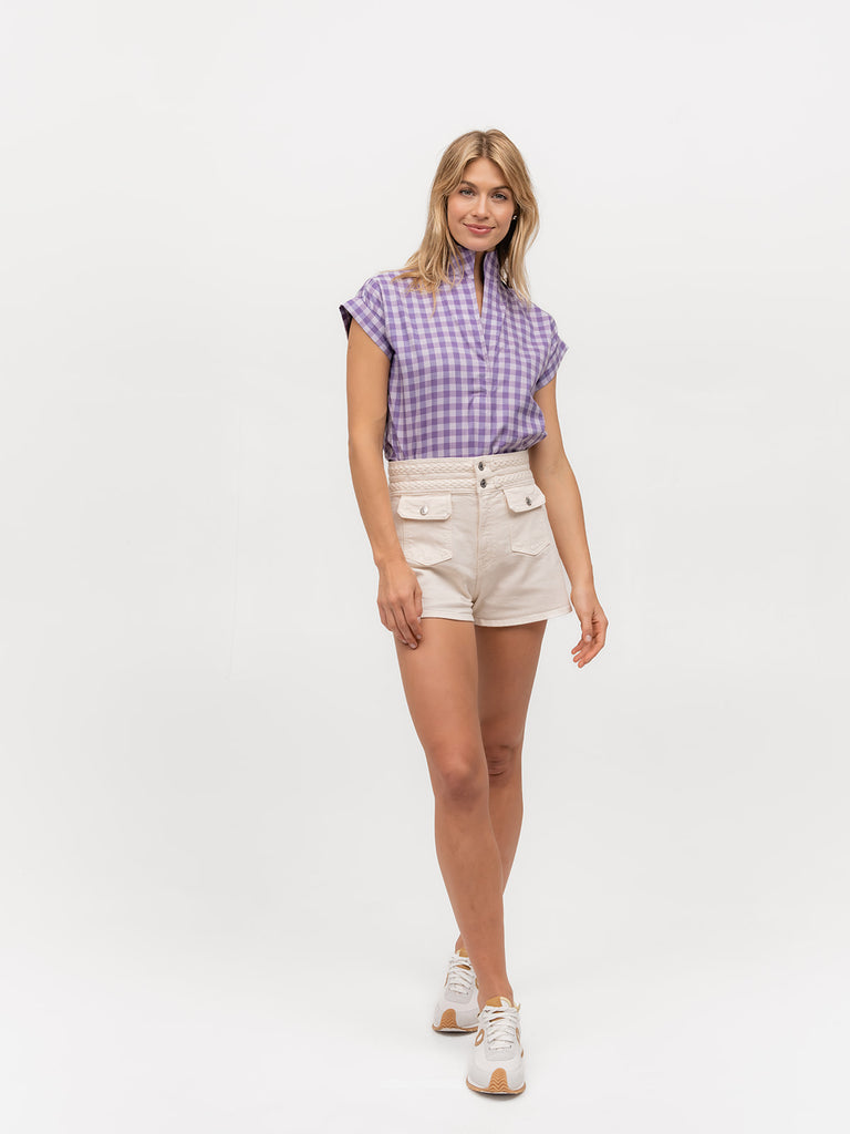 Woman wearing shorts with a purple checkered short sleeve shirt