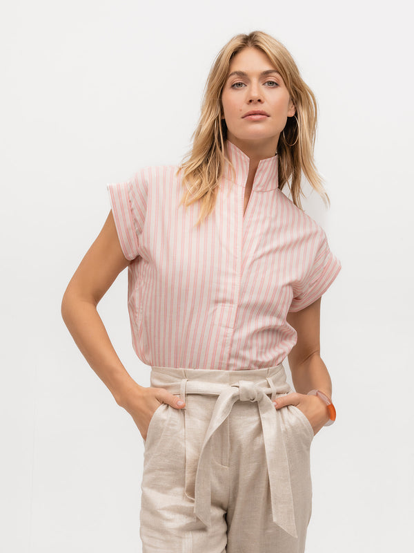 Woman wearing a luxury cap sleeve shirt with pink and cream stripes