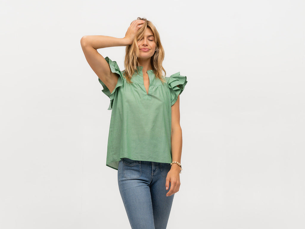 Woman wearing a short sleeve green flutter sleeve top