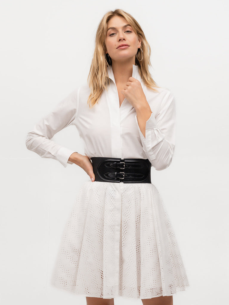 Woman wearing a high end blouse with a belt and short skirt