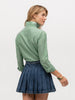 Back of woman wearing a muted green blouse with a skirt