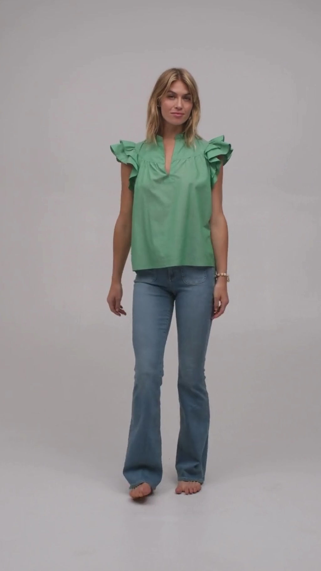 Model wearing a luxury flutter sleeve top in green Italian cotton