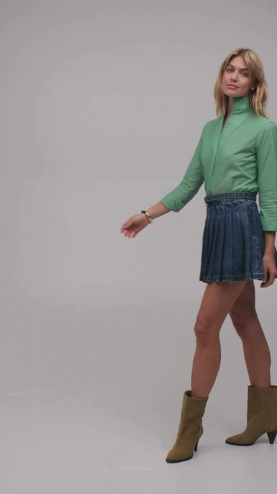 Beautiful woman modeling a green designer blouse with a short denim skirt and ankle boots