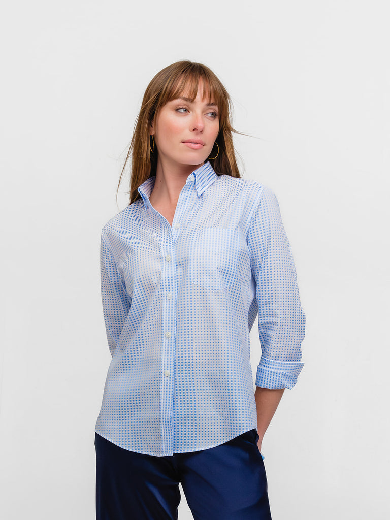 Woman gazing into the distance while wearing a light blue polka dot designer button-down shirt made of Italian cotton.